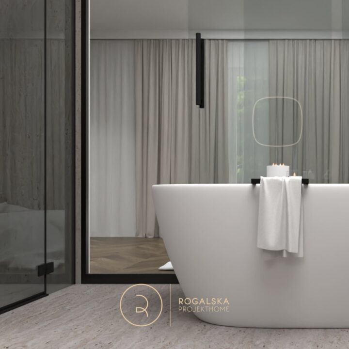 Wanna wolnostojąca na podłodze z szarego kamienia. Za przeszklonymi, przesuwnymi drzwiami widoczna jest sypialnia w odcieniach bieli i kaszmiru.